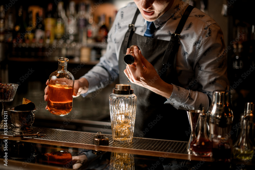 barman carefully pours drink to glassy shaker using beaker. barman carefully pours drink to glassy shaker using beaker.
