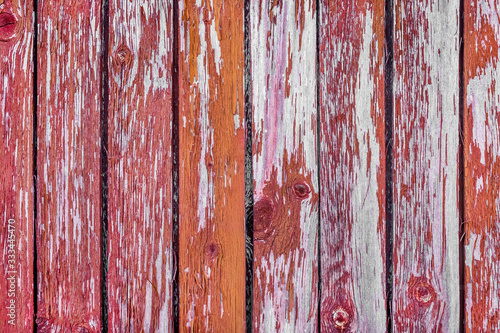 Peeling red paint texture of an old wooden fence with abstract natural pattern, background board