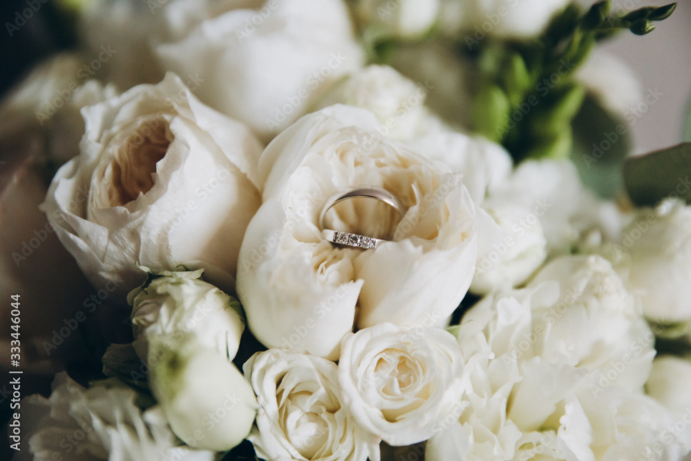 wedding ring lies on a bouquet of white flowers and greenery wedding ring lies on a bouquet of white flowers and greenery