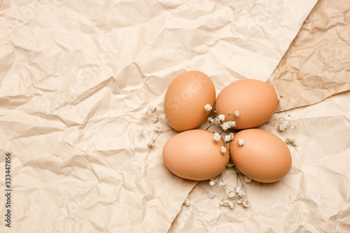 Brown fresh hen's eggs on wrinkled craft paper. Eco-friendly egg production. Bakery ingredients. Organic chicken eggs - fresh from producer. Trend of minimalism, top view. Free space for text.