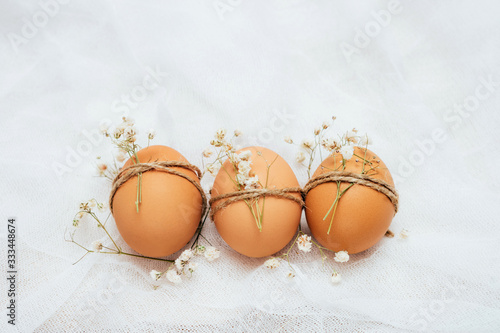 Decorated brown chicken's eggs on white background. Eeco-friendly egg production. Bakery ingredients. Organic chicken eggs - fresh from producer. Eco-friendly Easter concept. photo