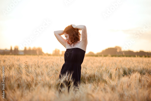 girl with clean skin and red hair in a wheat field during sunset