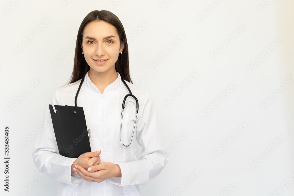 Friendly female doctor smiling holding a folder in her hands, a stethoscope on her neck Friendly female doctor smiling holding a folder in her hands, a stethoscope on her neck