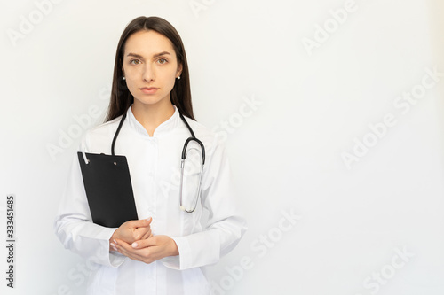 Friendly female doctor serious holding a folder in her hands, a stethoscope on her neck