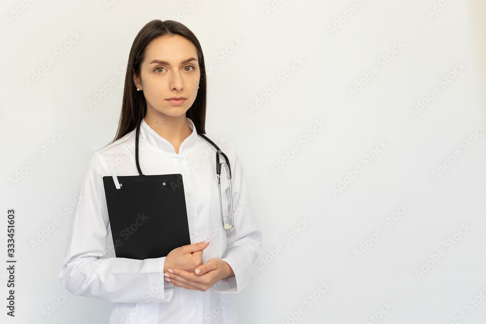 Friendly female doctor serious holding a folder in her hands, a stethoscope on her neck Friendly female doctor serious holding a folder in her hands, a stethoscope on her neck