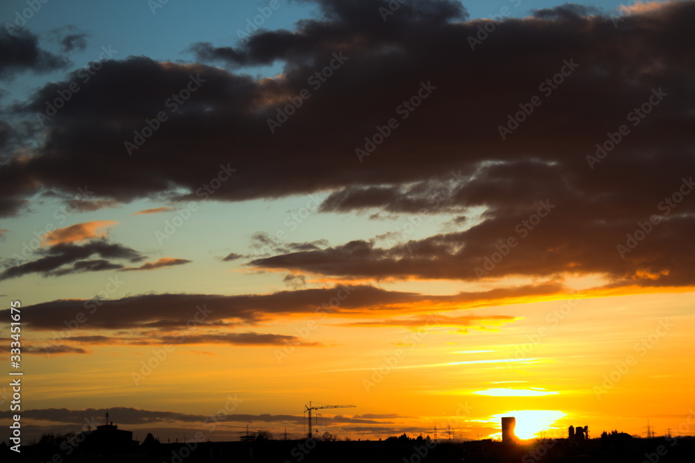 Sonnenuntergang, kleine Stadt mit Baukran als Silhouette