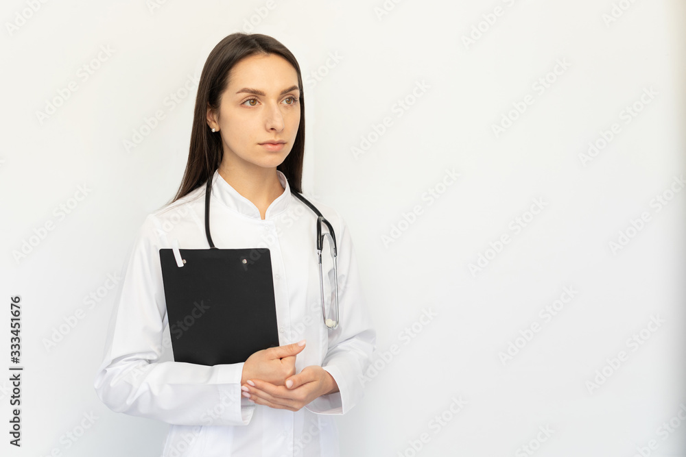 Friendly female doctor serious holding a folder in her hands, a stethoscope on her neck Friendly female doctor serious holding a folder in her hands, a stethoscope on her neck