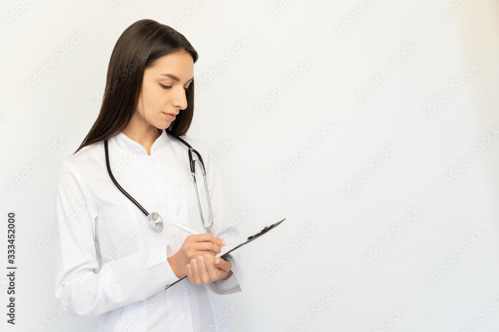 Friendly female doctor, writes the diagnosis to the clients card, a stethoscope on his neck Friendly female doctor, writes the diagnosis to the clients card, a stethoscope on his neck