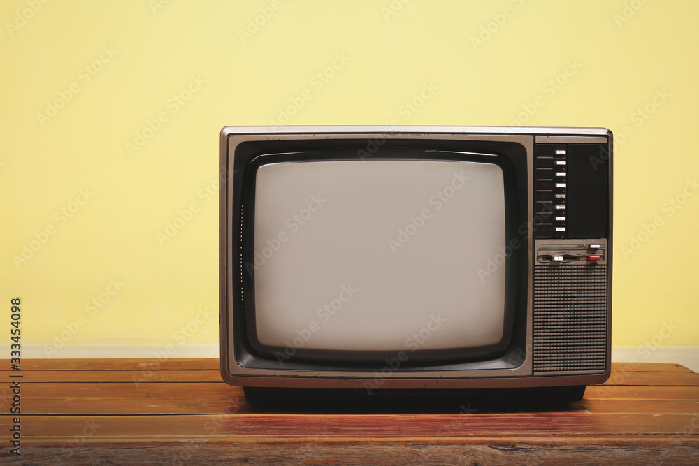 Retro old tv on wooden table with yellow concrete wall background. Retro old tv on wooden table with yellow concrete wall background.