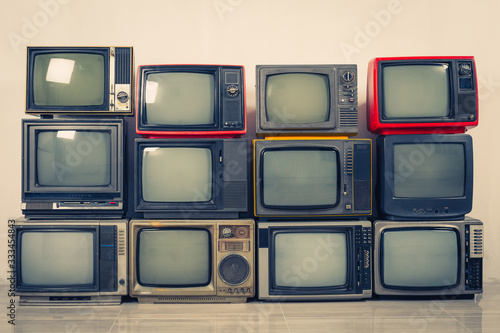 Retro old TVs pile on floor in the room. Television stack with vintage filter effect photo