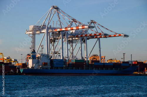 Logistics and container loading by large barges by sea in a harbor full of containers waiting to be transported