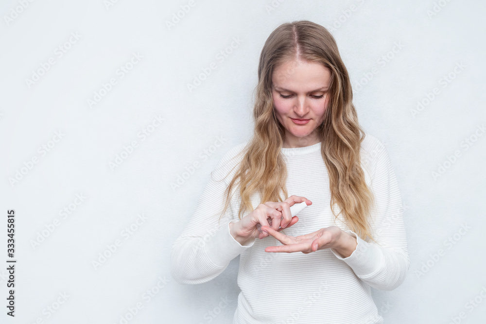Caucasian woman uses hand sanitizer on the light background with copy space Caucasian woman uses hand sanitizer on the light background with copy space