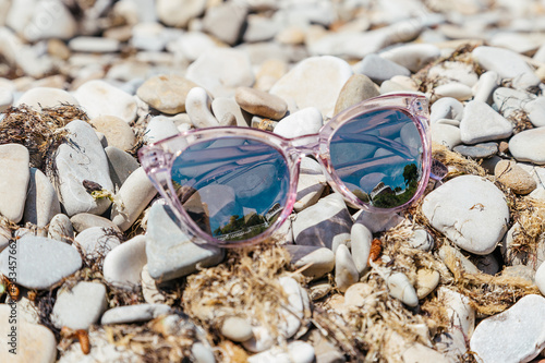 The reflection in the pink glasses on the beach. The concept of recreation and travel.