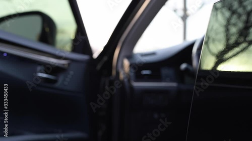 Woman is opening black car door and getting out car