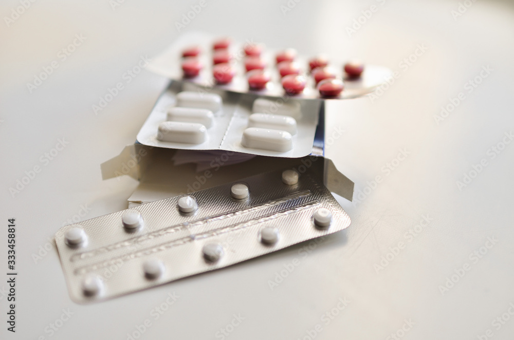 medical face mask and many different pills in blisters. Photo on a white background with bokeh. medical face mask and many different pills in blisters. Photo on a white background with bokeh.