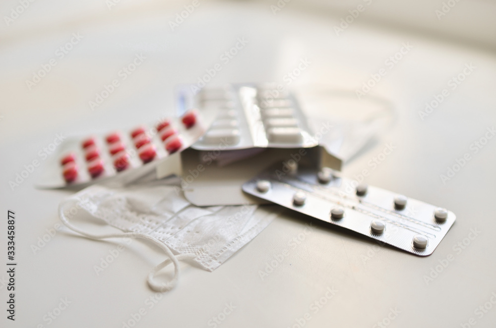 medical face mask and many different pills in blisters. Photo on a white background with bokeh. medical face mask and many different pills in blisters. Photo on a white background with bokeh.