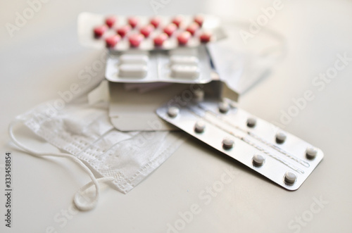  medical face mask and many different pills in blisters. Photo on a white background with bokeh.