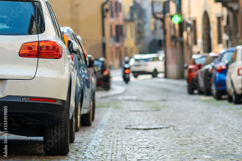 Modern cars parked on city street side in residential discrict. Shiny vehicles parked by the curb. Urban transportation infrastructure concept.