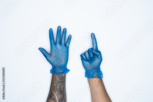 A man hand and gestures in Blue rubber glove shows six finger sign isolated on white background.