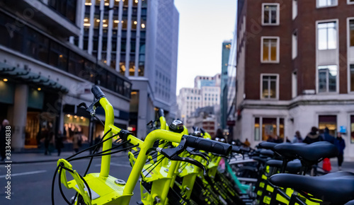 Photography Yellow electric hire bikes line a busy city street