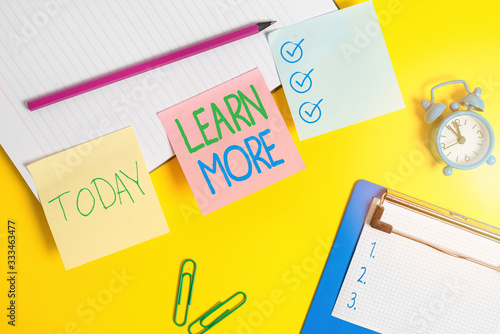 Text sign showing Learn More. Business photo text knowledge or skill acquired by instruction Considerable learning Flat lay above table with blank papers with copy space for text messages photo