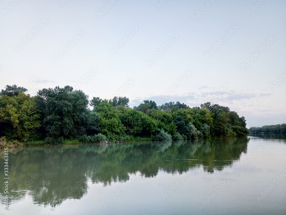 River landscape. River flow. Water surface and trees on shore. River landscape. River flow. Water surface and trees on shore.