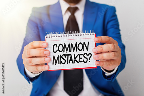 Writing note showing Common Mistakes Question. Business concept for repeat act or judgement misguided making wrong Man holds empty paper with copy space in front of him Space