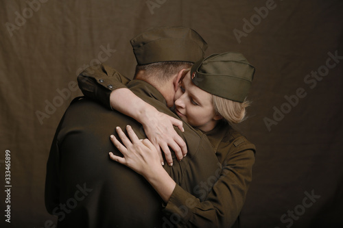 Young couple in love in world war Second military uniform hugs as if saying goodbye on brown background