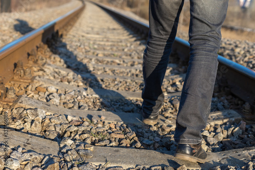 A man walks along the railway, crossing the sleepers. Reckless behavior.