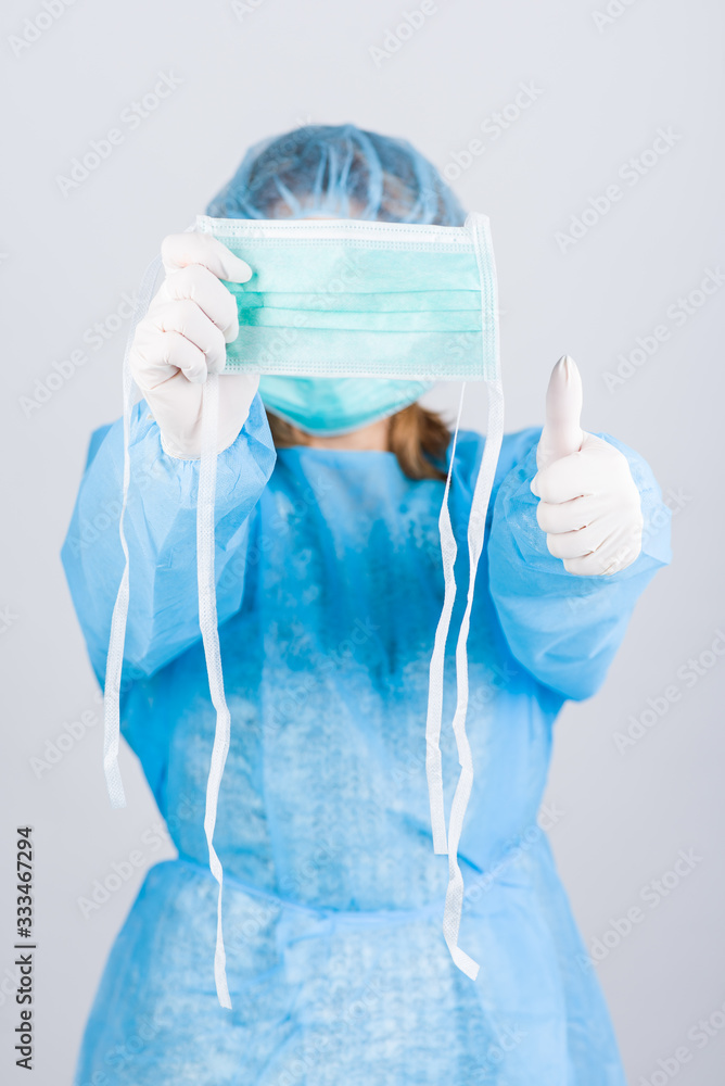 Naklejka premium Female doctor in medical uniform and gloves showing face mask. Stop the concept of CORONAVIRUS. Vertical