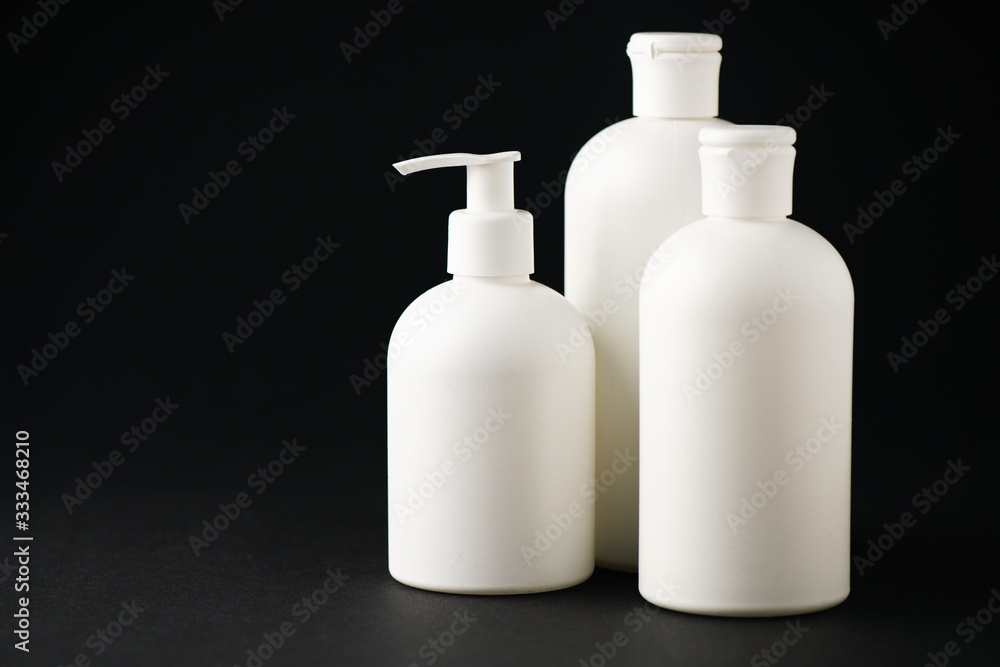 white bottles with cosmetics on black with copy space white bottles with cosmetics on black with copy space