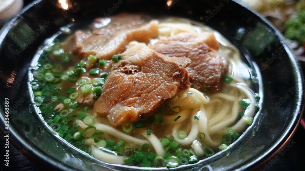 Asian style soup with udon noodles, pork, boiled eggs, mushrooms and green onions close-up in a bowl on the table. horizontal top view from above Asian style soup with udon noodles, pork, boiled eggs, mushrooms and green onions close-up in a bowl on the table. horizontal top view from above