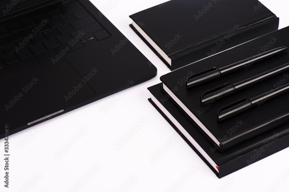 pens and notebooks near modern laptop isolated on white pens and notebooks near modern laptop isolated on white