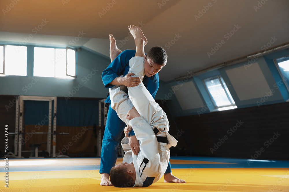 Two young judo caucasian fighters in white and blue kimono with black ...