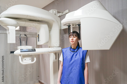 Young asian patient woman standing in dental x-ray machine for dental radiography.