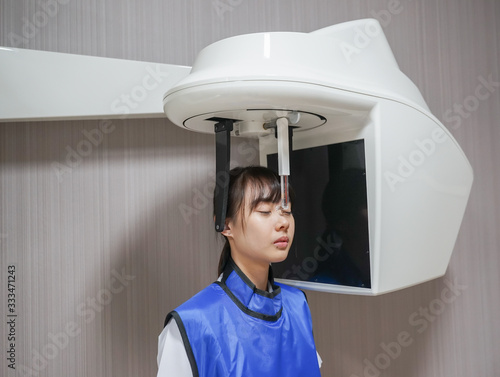 Young asian patient woman standing in dental x-ray machine for dental radiography.