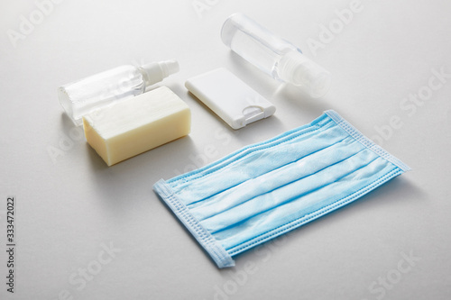 flat lay with hand sanitizer in spray bottles   medical mask and antibacterial soap on grey background