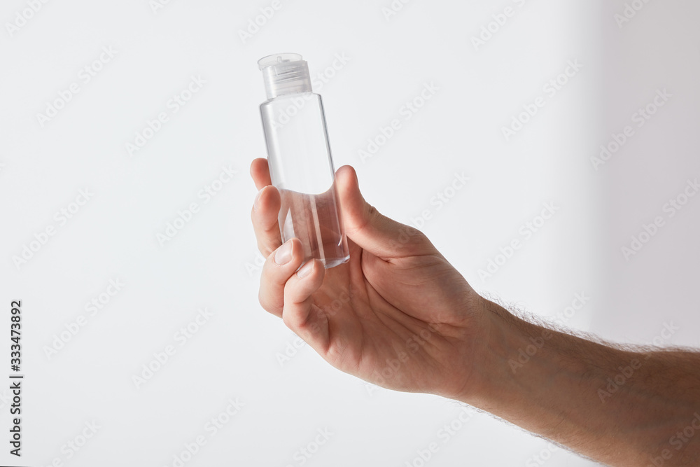 cropped view of man holding hand sanitizer on grey background cropped view of man holding hand sanitizer on grey background
