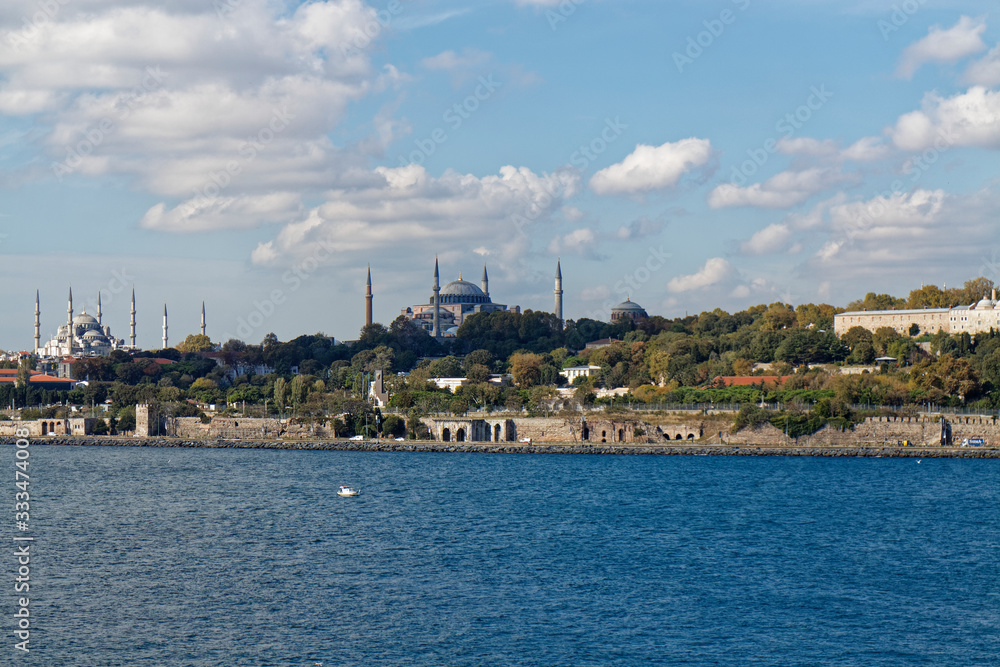 The tree lined grounds of the Topkapi Palace with its fortified walls along the shoreline of the Bosphorus Straits.