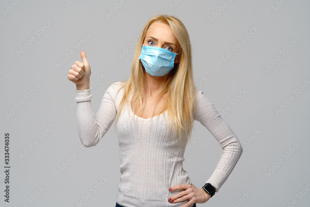 Studio portrait of young woman wearing a face protective mask isolated on gray background - flu virus epidemic protection, dust or pollen allergy, air pollution Studio portrait of young woman wearing a face protective mask isolated on gray background - flu virus epidemic protection, dust or pollen allergy, air pollution