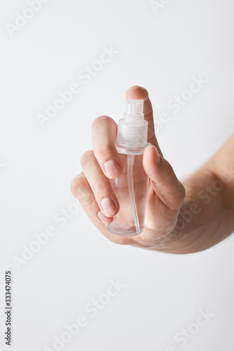 cropped view of man holding hand sanitizer in spray bottle isolated on white