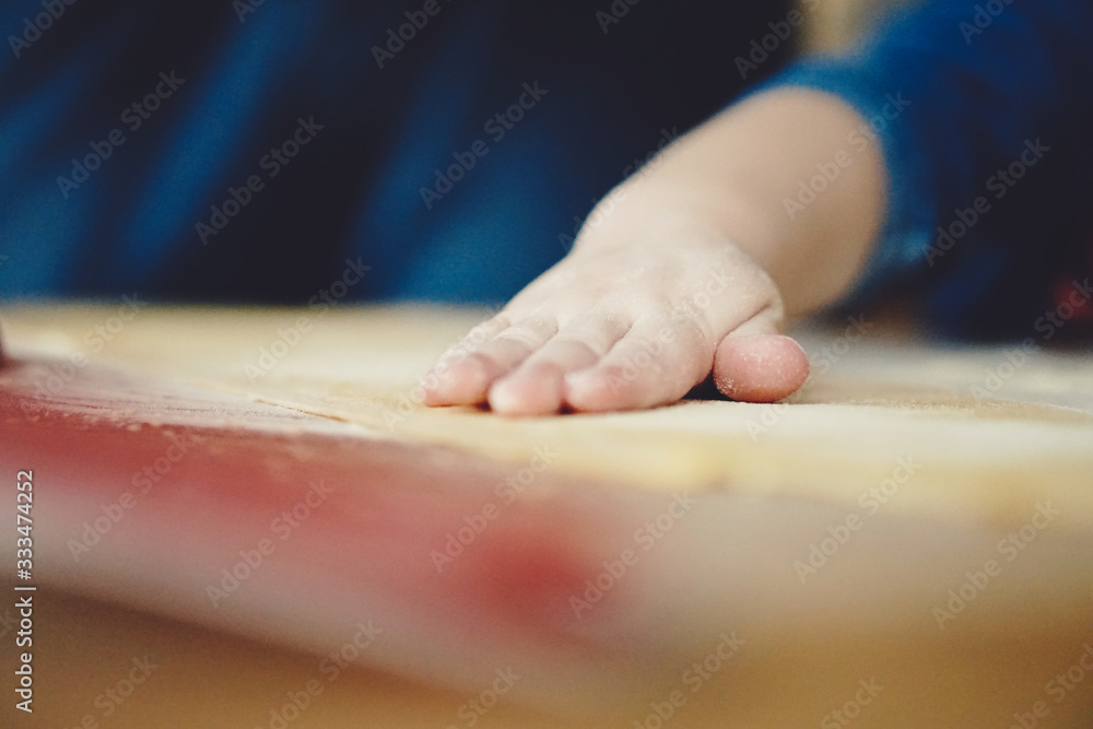 Obraz premium childs hands kneading dough on table