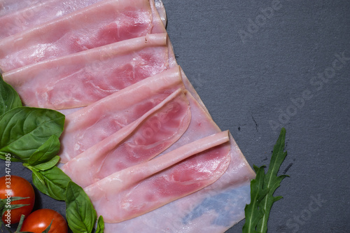 Tasty fresh red ham with basil leaves and cheery tomatoes