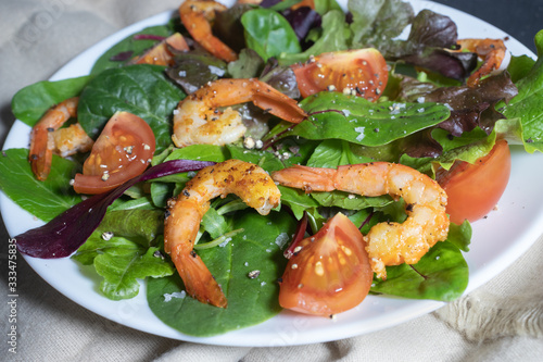 Grilled shrimps, vegetables and herbs salad on a plate