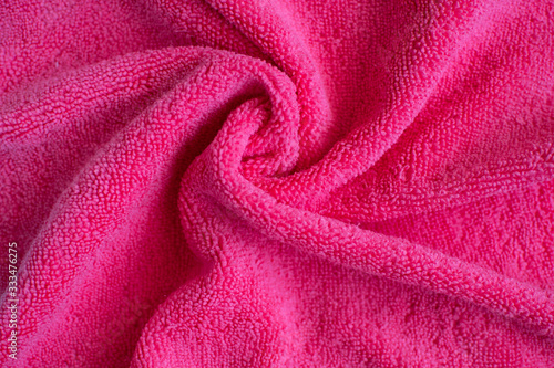 Wrinkled bright pink microfiber cloth texture of microfiber towel closeup. Pink microfiber cloth for cleaning objects and surfaces. Hygienic cleaning towel. fabric background.