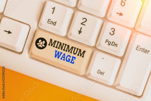 Writing note showing Minimum Wage. Business concept for the lowest wage permitted by law or by a special agreement photo