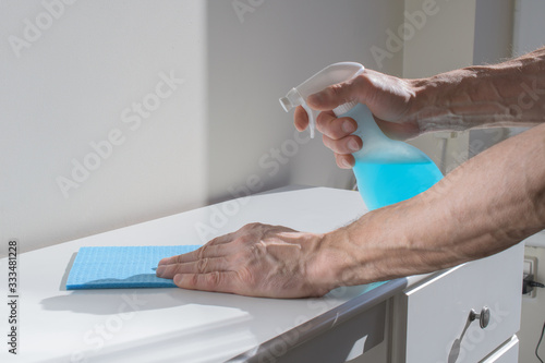  close up of man hands cleaning table with cloth and detergent spray at home