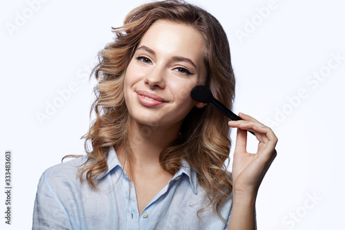 Smiling happy girl with make up brush on white background. 