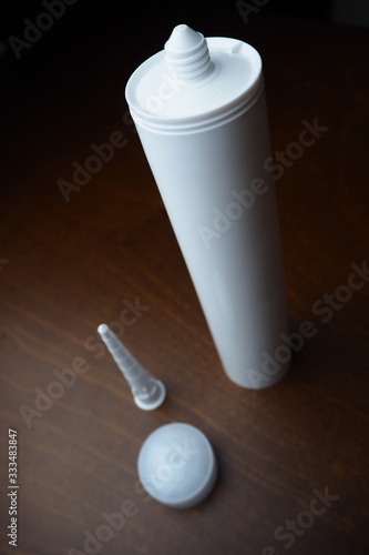 Part of sealant cartridge. Sealant cartridge on the table. White caulk on wood table. Sealant for fix water leak.
