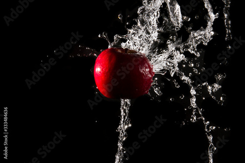 The water splashes on the apple until the water is distributed beautifully on a black background.